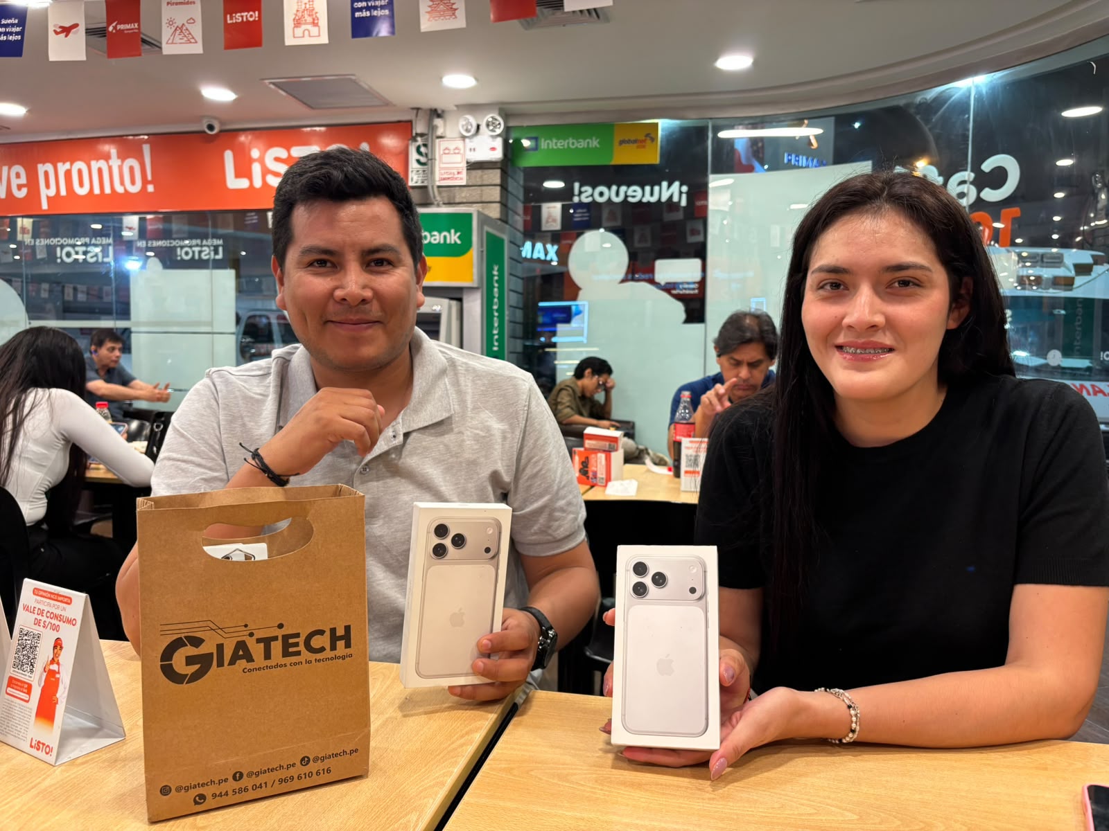Dos clientes con sus cajas de iPhone y una bolsa de GIATECH.